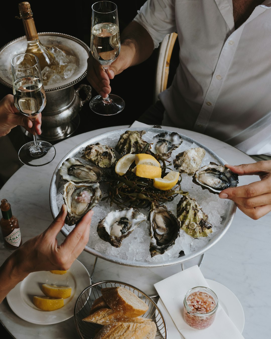 a-table-topped-with-oysters-and-wine-glasses-pbbyn1oaw78